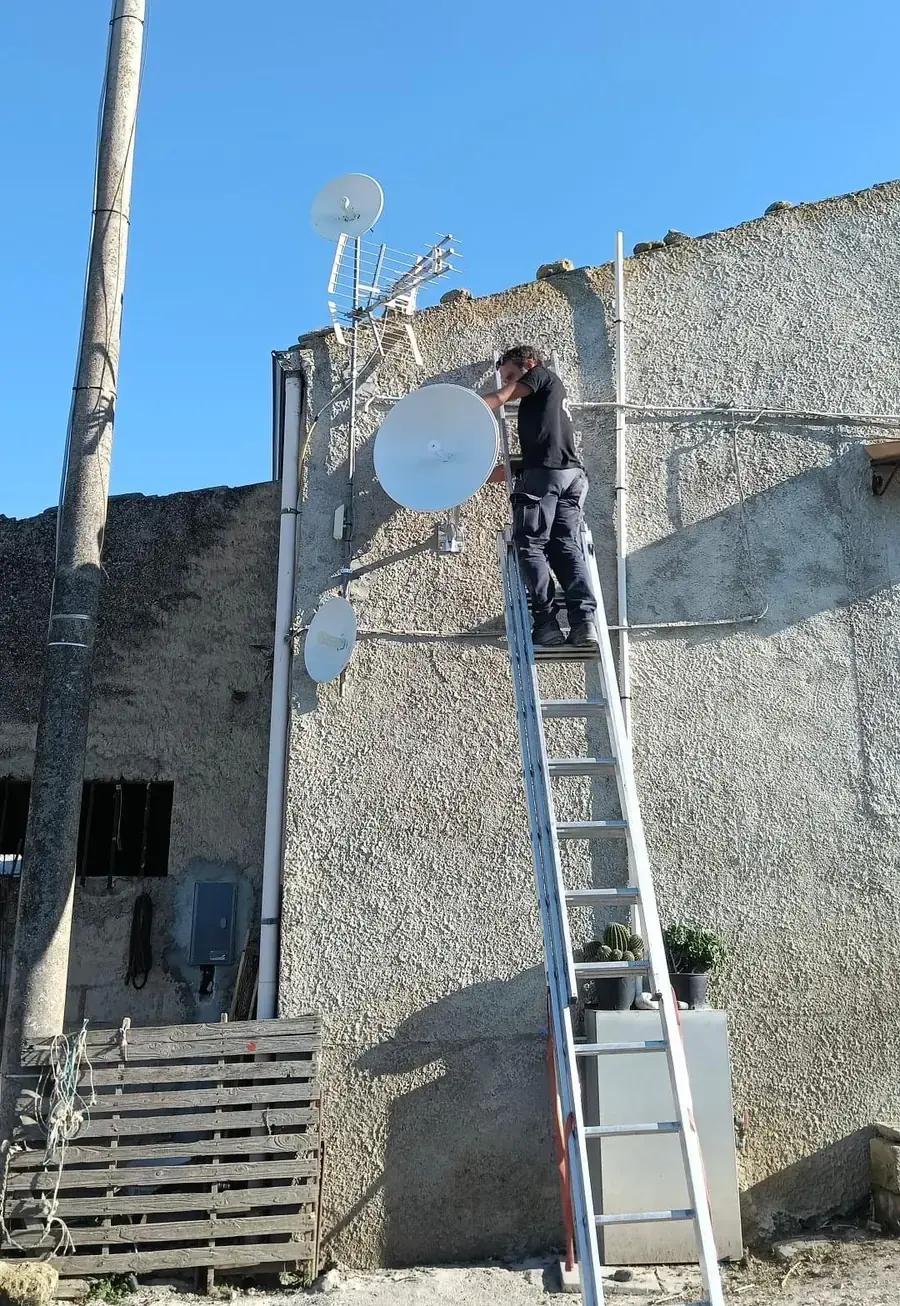 Tecnico Lo Voi Service sulla scala monta le antenne per la connessione Internet